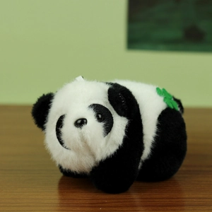 Schattige panda pluchen sleutelhanger met groen blad op houten oppervlak