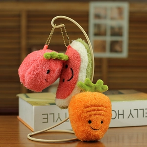 Macro shot of plush fruit charms with carrot and watermelon shapes on gold chains