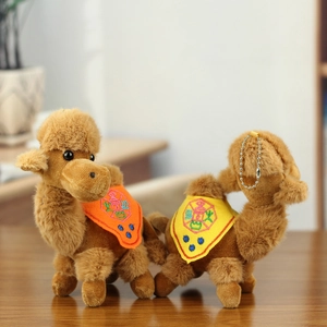 Close-up of plush camel keychains with vibrant traditional embroidery on wooden surface