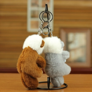 Dettaglio di portachiavi a forma di orsetto di peluche marrone e grigio con ganci