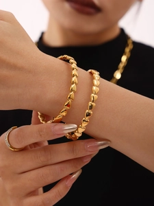 Détail de deux bracelets perlés dorés avec cœurs empilés au fini poli sur mannequin