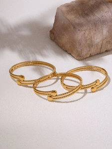 Dettaglio di tre bracciali a doppio strato placcati in oro 18k con terminali a sfera su pietra
