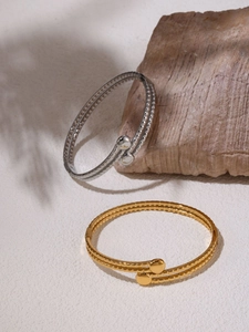 Dettaglio di bracciali aperti minimalisti a doppio strato con finitura oro e argento
