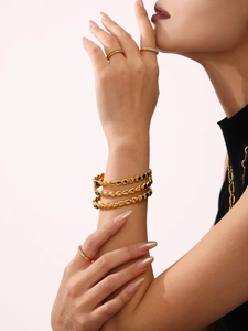 Détail d'un bracelet à maillons cœur plaqué or 18 carats et de bagues sur un mannequin