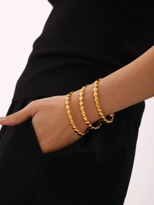 Détail du bracelet chaîne en forme de cœur plaqué or 18 carats au poignet d'une femme