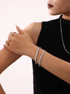 Gros plan d'un bracelet à maillons cœur argenté poli au poignet avec des bagues