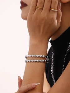Gros plan d'un bracelet à maillons en cœur en acier inoxydable poli argenté pour femme