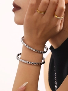 Detailed view of silver beaded cuff bracelets with polished metallic finish on a model wrist