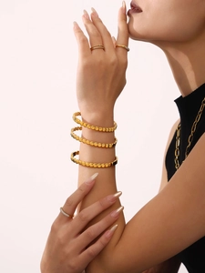 Detail of 18K gold plated spiral cuff bracelet with metallic dot texture on model