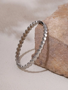 Detailed view of silver beaded cuff bracelet resting on natural stone with polished finish