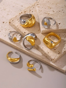 Dettaglio di un set di sette anelli geometrici in oro e argento su pietra travertino