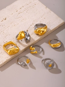Dettaglio ravvicinato di anelli scultorei bicolore placcati in oro 18K su pietra beige