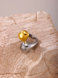 Dettaglio macro di anello geometrico bicolore con sfera dorata su fascia argento