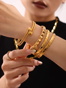 Detail of 18K gold-plated titanium bangles with textured patterns and sparkling accents