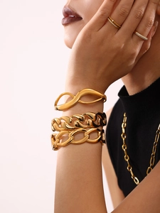 Detail of 18K gold-plated titanium bangles and Cuban chain bracelet on wrist