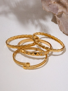Detail of 18K gold-plated titanium bangles with quilted texture and studded accents