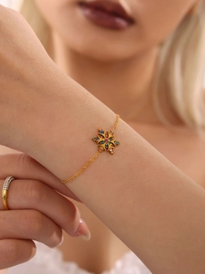 Detalle de una pulsera de copo de nieve bañada en oro de 18K con circonitas de colores