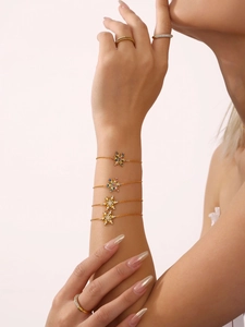 Detalle de pulseras doradas con copos de nieve y circonitas en la muñeca