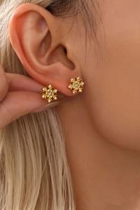Close-up van een model met gouden sneeuwvlok oorbellen met fonkelende zirkonia