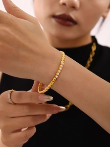 Detail of a gold-plated pearl bracelet on a model wrist with a minimalist luxury style