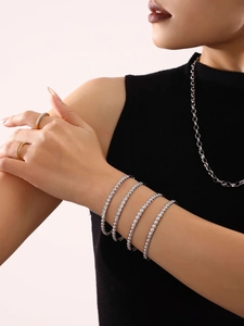 Close-up of model wearing silver tennis bracelets and gold pave rings with zircon stones