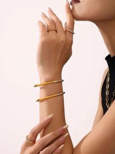 Detail of hand-set zircon bracelets and rings in gold-plated stainless steel on a model