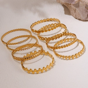 Goldenes Titanstahl-Armband-Set mit weißen Zirkonia und Perlen auf beigem Hintergrund