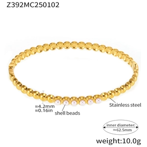 Detail of gold beaded stainless steel bangle with shell pearl inlay and textured finish