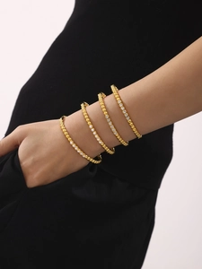 Detail of four-piece gold bracelet set with pearls and crystals on female model wrist