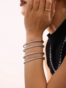 Detailed view of layered silver beaded bracelets with crystals and gold stacking rings