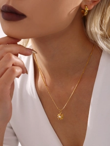Gros plan d'un collier pendentif perle tournesol doré et de boucles d'oreilles en C
