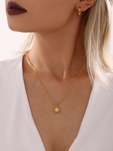 Gros plan d'un collier pendentif tournesol doré 18K avec perle centrale porté par un modèle