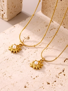 Détail du collier pendentif perle soleil plaqué or 18K sur socle en travertin beige