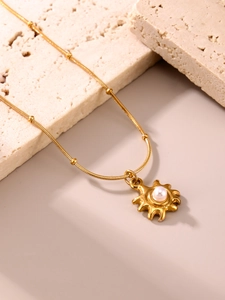 Détail du collier pendentif tournesol plaqué or 18 carats avec perle sur travertin