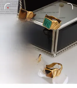 Close-up of four vintage gold rings with square tiger eye and malachite gemstones
