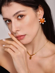 Gros plan sur les boucles d'oreilles perles orange et collier avec pendentif rectangulaire