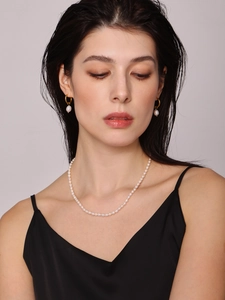 Close-up of model wearing baroque pearl necklace and golden drop earrings set