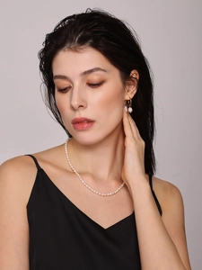 Close-up of elegant freshwater pearl necklace and gold hoop earrings on a model