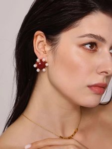 Gros plan d'une boucle d'oreille vintage en émail rouge et perles sur un mannequin