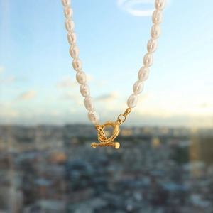 Detailed close-up of freshwater pearl necklace with textured golden OT toggle clasp