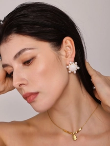 Gros plan de boucles d'oreilles en perles blanches avec incrustation d'or sur un modèle