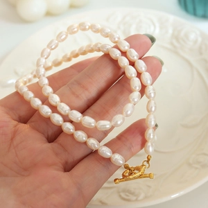 Detailed view of Baroque freshwater pearl necklace with gold OT buckle on white plate
