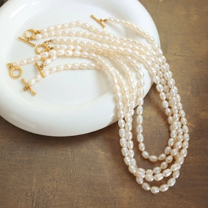 Macro shot of natural baroque pearl necklaces with golden toggle clasps on a white plate