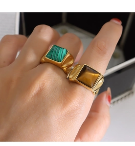 Close-up of square gold-plated rings featuring natural malachite and tiger eye stones