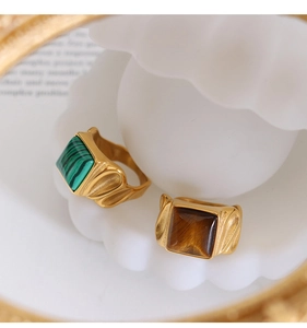 Macro shot of vintage gold rings with malachite and tiger eye stones in a shell tray