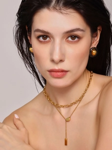Detail of layered gold necklace and vintage-style resin stud earrings on a model