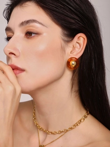 Detail of model wearing amber resin earrings and layered gold-plated necklaces