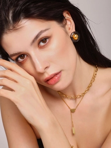 Detail of PVD gold plated chain necklace and resin inlay earrings on a model