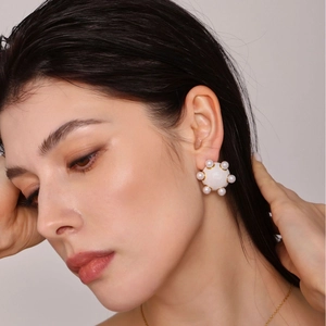 Boucles d'oreilles dorées avec agate blanche et petites perles sur un mannequin