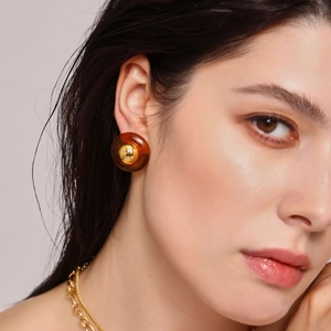 Amber resin earrings with gold sphere center on model wearing a chunky gold chain